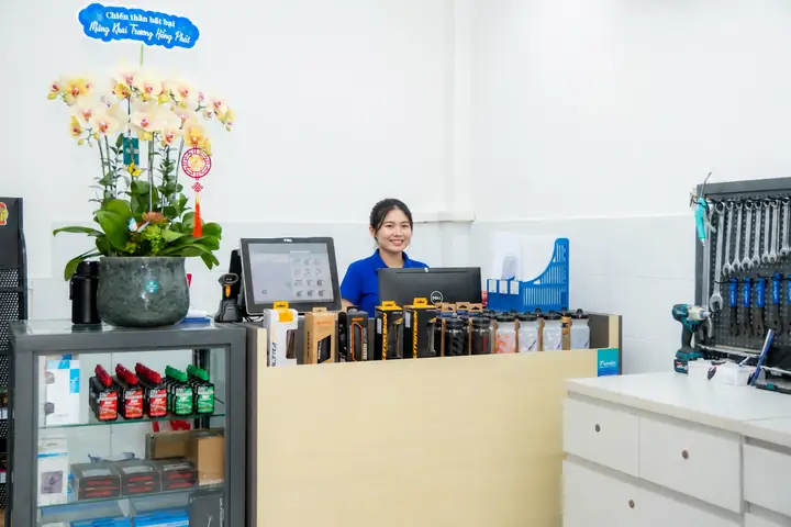Quầy thu ngân của cửa hàng xe đạp, nhân viên đứng sau quầy cạnh bình hoa lan